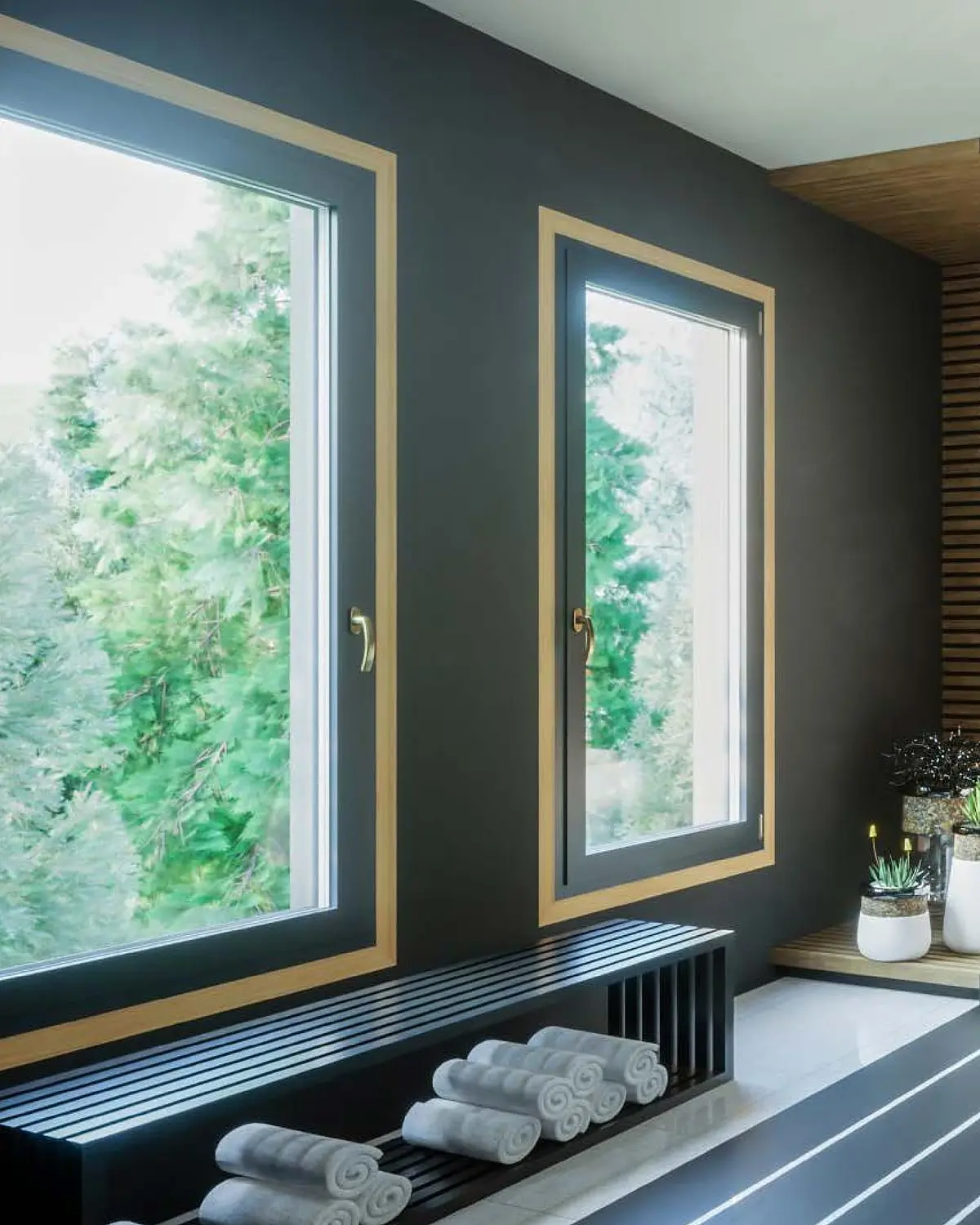 Zwei Fenster in Holzdekor in einer dunklen Wand, davor eine niedrige Bank über dem Heizkörper