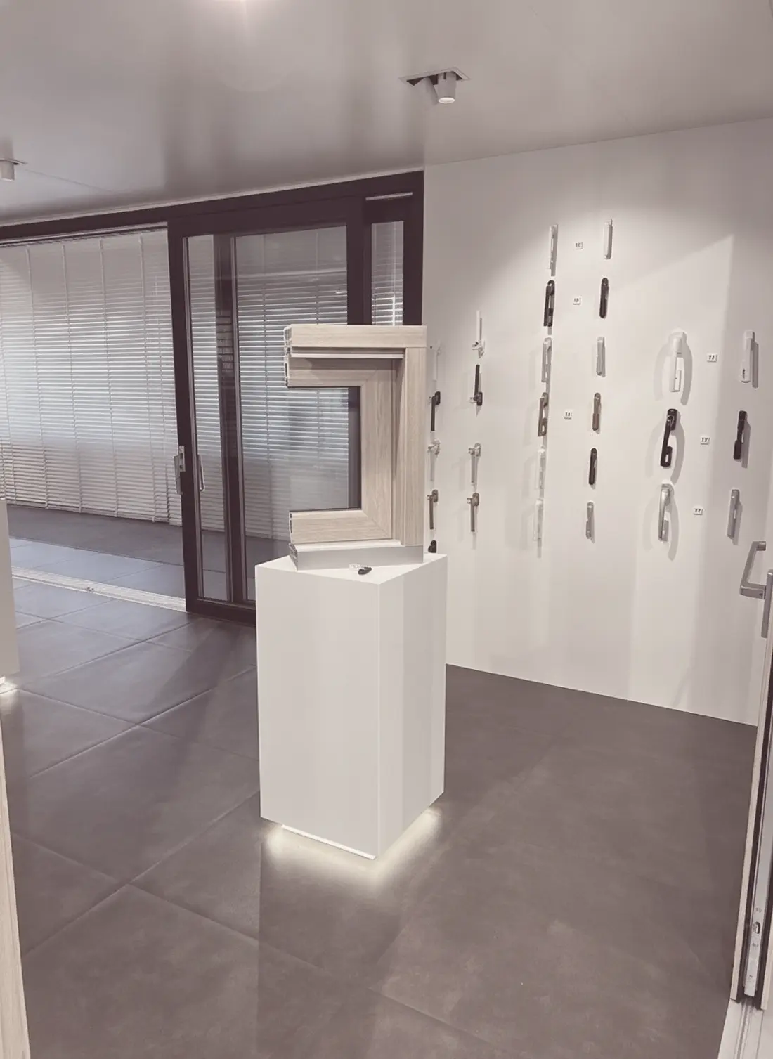 Profilmuster auf einem Podest, dahinter eine Wand mit Griffen im Ausstellungsraum