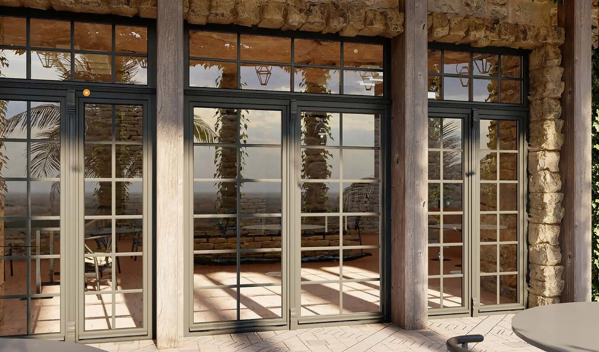 Überdachte Loggia mit hohen, dunkel gerahmten Fenstertüren vor einer alten Bruchsteinwand